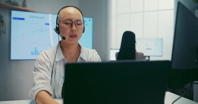Young Asian female agent talking on phone headset consulting client online in call center office. Corporate customer service, technical support, remote tech operator, business team help desk concept.