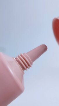 Process of opening a pink product packaging cap. Close up view. Beauty or skincare product, unboxing or daily routine concept on clean background.