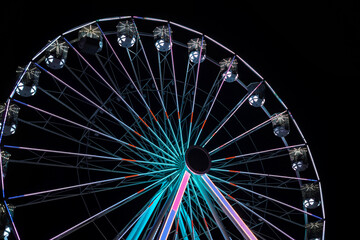 Illuminated Ferris wheel with colorful LED lights against black night sky © Valentina