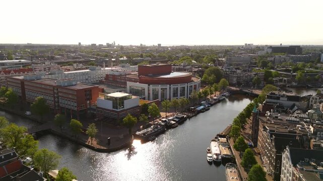 Aerial drone flies toward Amsterdam waterfront revealing modern cultural buildings along the historic IJ river shore