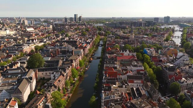 Drone circles above Amsterdam historic center revealing the interconnected canals and red-roofed city skyline