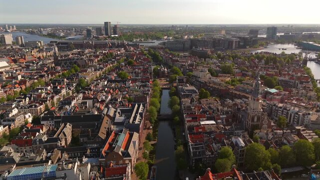 Aerial drone flies above Amsterdam parallel historic canals lined with trees and dense brick canal houses