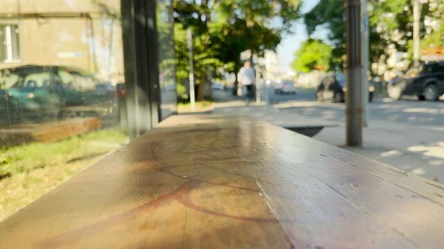 A man walks away past an empty wooden bench at a sunny bus stop in Simferopol, Crimea. The quiet scene brings a lonely and nostalgic feeling.