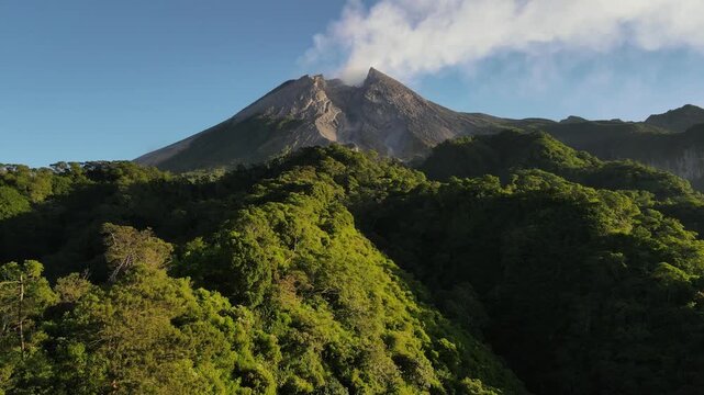 Aerial view of Mount Merapi Volcano at Sunrise, Yogyakarta, Indonesia. Mount Merapi illuminated by sunrise, with lush tropical forest covering its lower slopes and dramatic volcanic scenery