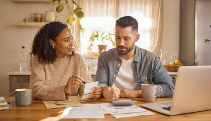 Fototapeta premium Serious diverse couple sitting at home dining table reviewing financial documents calculating household budget and managing family expenses