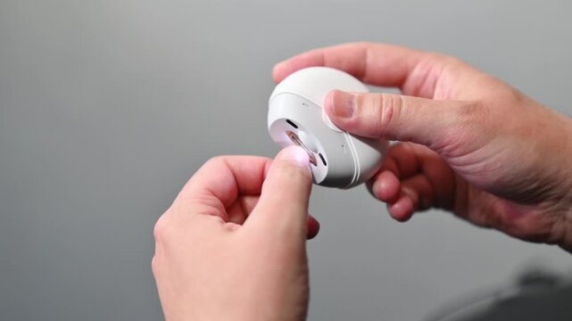 Person carefully trimming fingernails with modern electronic nail clipper device