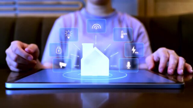 A person using a tablet to control a smart home system with digital hologram icons for lighting, security, energy, and IoT connectivity, representing modern home automation technology.