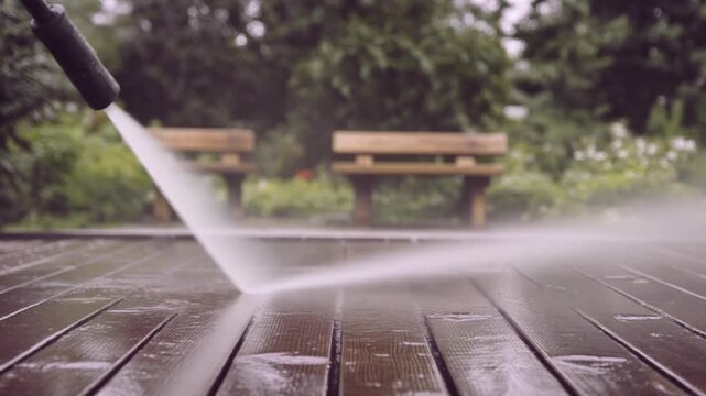 ウッドデッキの木目に高圧洗浄機の白い水流が広がる