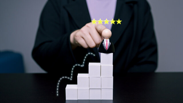 Businessman wooden doll on top of block stairs with a five star rating and growth line graphics, representing career success, top performance, and excellent customer satisfaction.