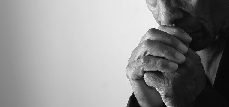 A serene portrait of a man praying with hands together in deep prayer that perfectly captures themes of faith, hope, mindfulness, and inner peace stock image stock photo