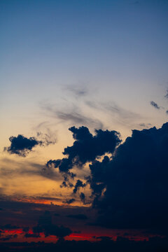 Dramatic sunset sky with dark silhouettes clouds. Beautiful sunset sky with dark cloud over vibrant orange red and deep blue gradients representing natural beauty majesty and stormy weather concept
