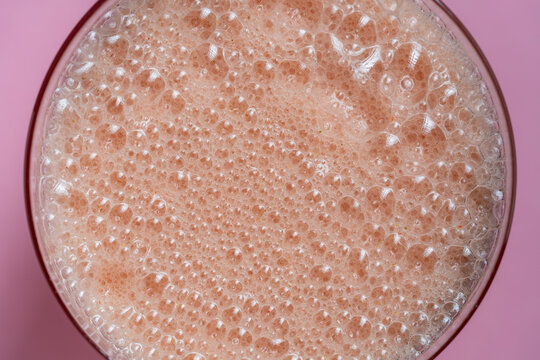 Fresh strawberry smoothie or milkshake with bubbles in glass on pink background, top view. Minimalist flat lay for cafe menu morning routine beverage catering or summer sweet dessert promotion