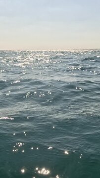 Ocean water waves, shimmering sunlight reflections on deep blue sea creating a peaceful tranquil natural beauty