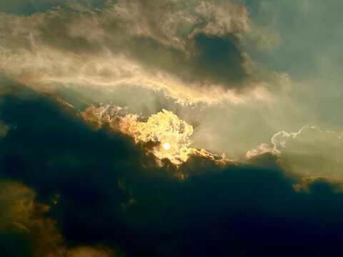 Golden sun breaking through dramatic dark storm clouds during sunset
