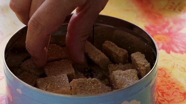 Womans hand choosing and picking shortbread cookies from a round metal tin. Everyday kitchen scene with biscuits, homemade snack, sweet treat
