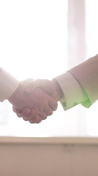 Camera moving during a business handshake with a cinematic lens flare against a bright light