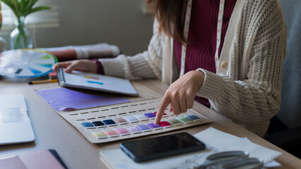 Fashion designer selecting fabric colors from palette swatches at creative studio workspace © Audtakorn