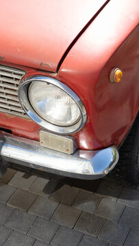 Front detail of a vintage VAZ 2101 classic Soviet-era car showing aged paint, corrosion and chrome elements in urban outdoor setting
