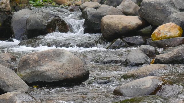 Closeup loop of gentle clear water flowing between mossy rocks. Perfect for ambient loops, meditation, background visuals, and nature scenes.