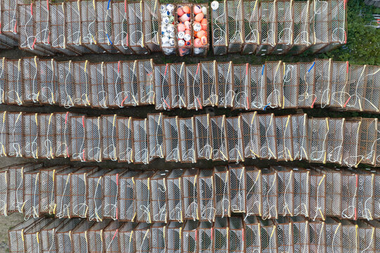 Aerial view of rows of stacked metal crab pots with colorful buoys in Unalaska, Alaska, United States.
