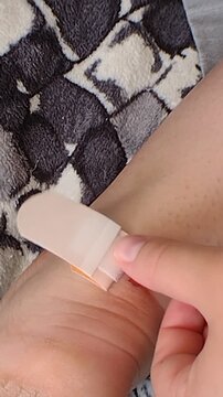 A person applying an adhesive bandage plaster to a bleeding blister wound on their foot heel. Vertical stock footage for first aid care, footwear friction injuries, and skin protection.