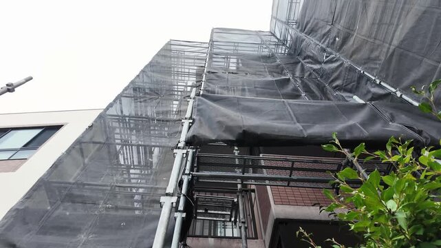 建物メンテナンス中の外壁タイルと鉄骨足場の背景