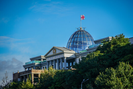 Orbeliani Presidential Palace with iconic glass dome and Georgian flag against blue sky in Tbilisi, Georgia