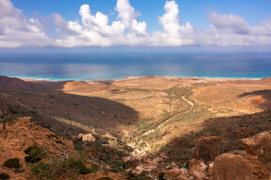 Aerial view of the Homhill infinity pool area featuring rugged arid terrain, rocky cliffs, and a distant view of the turquoise sea in Siqirah, Socotra, Yemen.