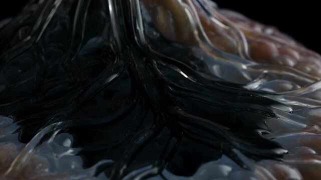 Abstract macro close up of dark viscous liquid flowing over a textured organic surface.