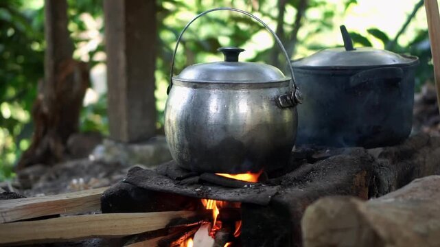 Traditional outdoor cooking with metal pots on open wood fire