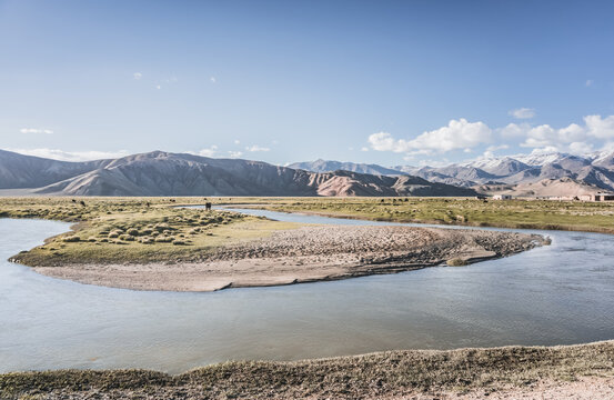 Clear-water rivers and lakes in a mountain valley, pastures and green grassy fields set against mountain ranges and snow-capped, glacier-clad peaks&mdash;a scenic landscape background