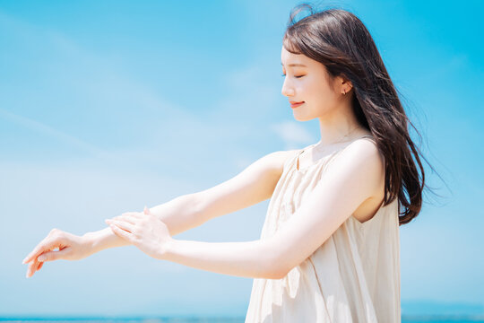 海で日焼け止めを塗る若いアジア人女性