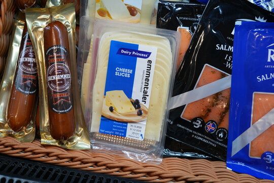 Packaged cheese, sausage, and salmon in a grocery basket.