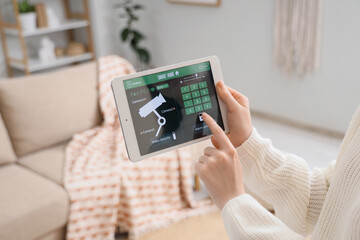 Person controlling smart home security system on tablet indoors © Pixel-Shot