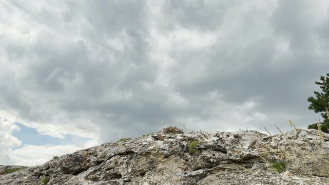 A rugged rocky peak stands under heavy storm clouds in Simferopol, Crimea. This powerful scene brings a dramatic and lonely feeling. The dark sky feels intense and moody.