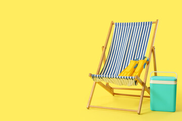 Beach chair with flippers and cooler on yellow background © Pixel-Shot