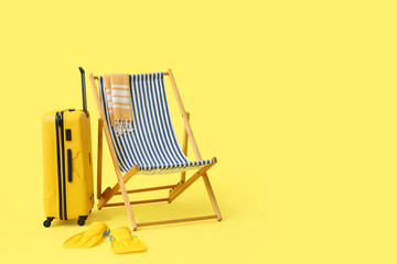 Beach chair with suitcase and flippers on yellow background © Pixel-Shot