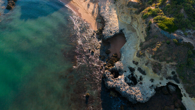 serene coastal landscape with wave interaction on rocky shoreline, aerial view of ocean and sand, beach and cliff setting, greenish-blue and brown tones, nature photography, vacation, Praia dos Aveiro