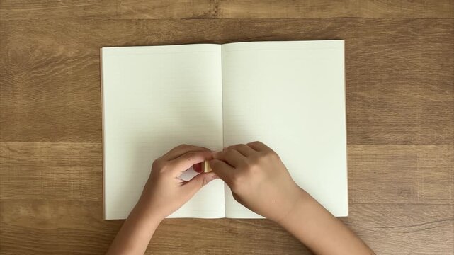 Child's Hands Peel a Light Brown Sticky Note and Press It onto a Lined Notebook, 4K