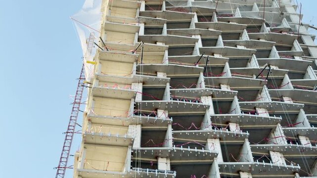 A high-rise building rises under construction in Simferopol, Crimea. This massive skeletal frame stands against a clear sky, evoking a feeling of progress and hopeful ambition for the future.