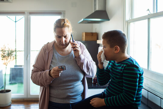 Worried mother calling doctor for sick son at home