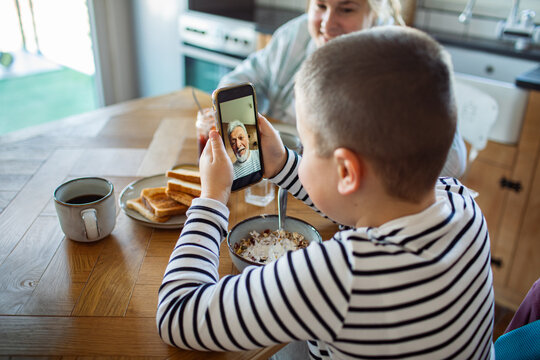 Boy video calling grandfather during breakfast at home
