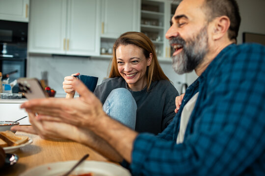 Happy couple video calling at breakfast in home kitchen