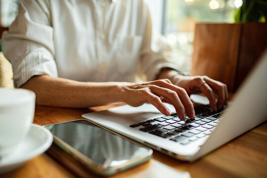 Hands typing on laptop in coffee shop