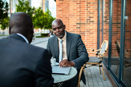 Two businessmen meeting at outdoor city cafe