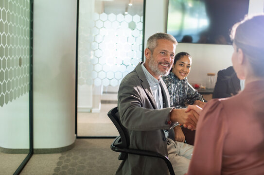 Business colleagues shake hands in modern office meeting room