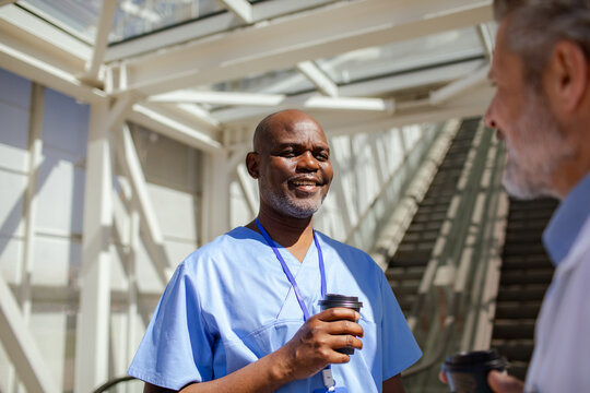 Smiling healthcare worker on coffee break in hospital atrium