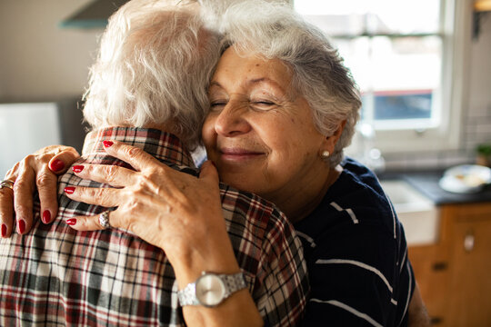 Smiling senior couple hugging in home kitchen