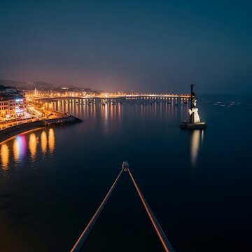 Illuminated Coastal Bridge and Harbor Lights Reflecting on Calm Bay at Night