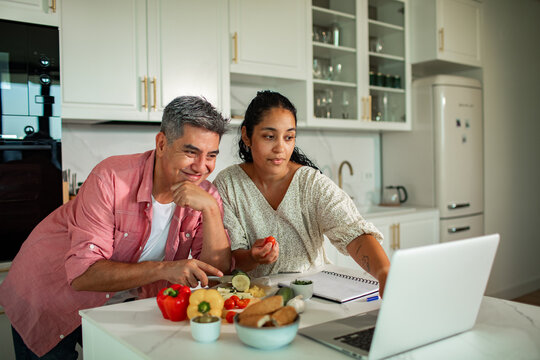Couple preparing vegetables while following an online recipe in a home kitchen